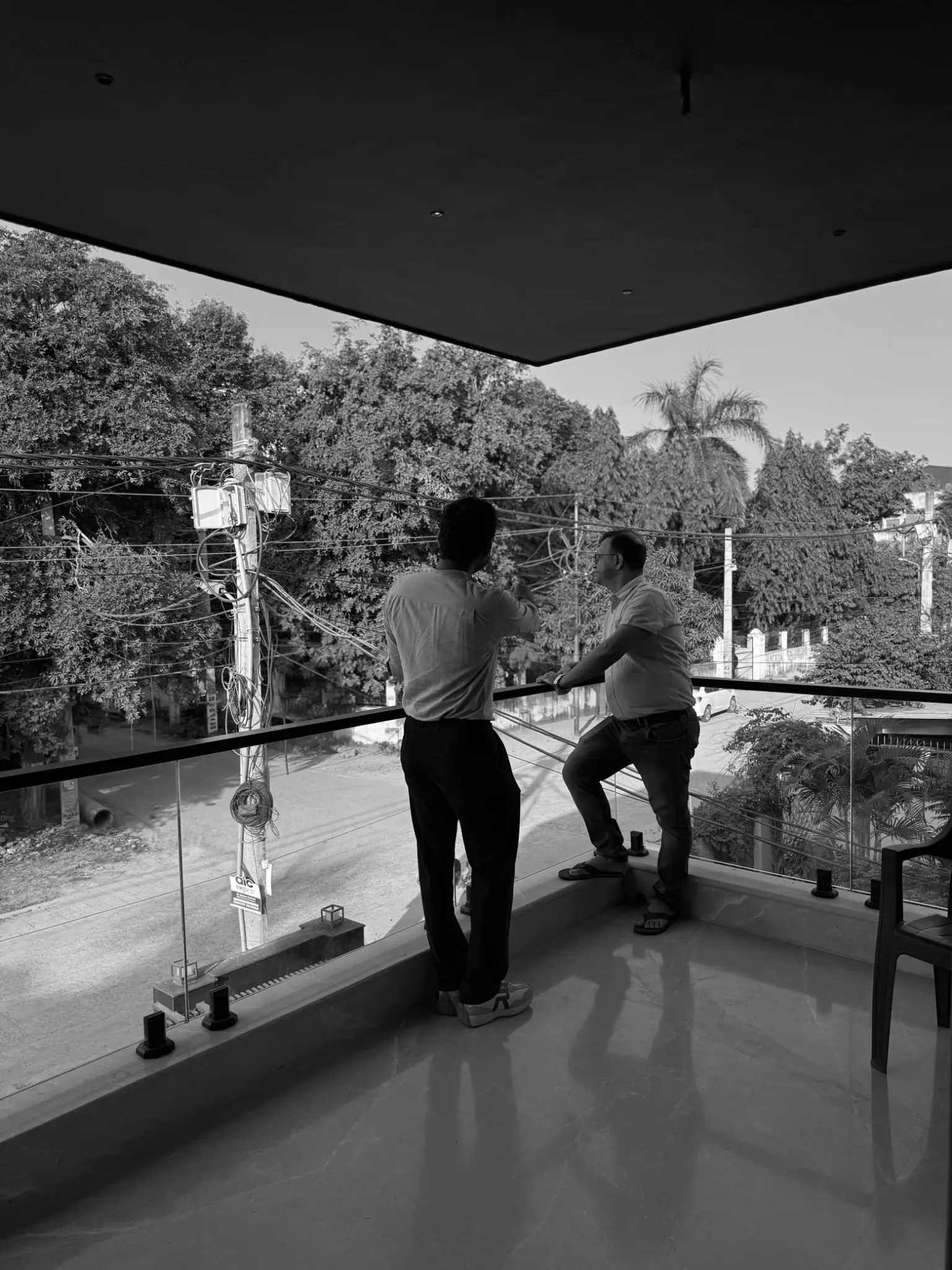 Black-and-white photograph of two people standing at the glazed balcony edge